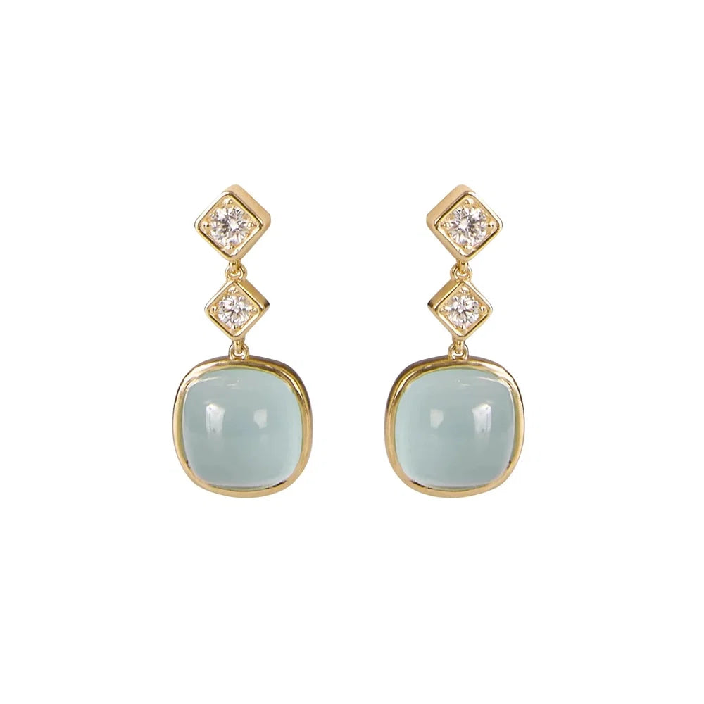 A pair of 18K yellow gold drop earrings each featuring a two diamonds and a large, smooth, light aqua blue cabochon stone below, set against a plain white background.