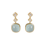 A pair of 18K yellow gold drop earrings each featuring a two diamonds and a large, smooth, light aqua blue cabochon stone below, set against a plain white background.