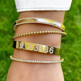 Woman wearing multiple gold and diamond bangle bracelets