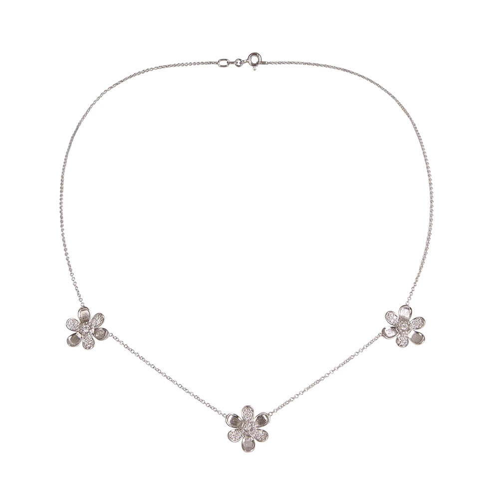 A delicate 18K white gold chain necklace featuring three small flower-shaped pendants, each adorned with clear pave diamonds, arranged symmetrically on a plain white background.