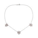 A delicate 18K white gold chain necklace featuring three small flower-shaped pendants, each adorned with clear pave diamonds, arranged symmetrically on a plain white background.