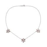 A delicate 18K white gold chain necklace featuring three small flower-shaped pendants, each adorned with clear pave diamonds, arranged symmetrically on a plain white background.