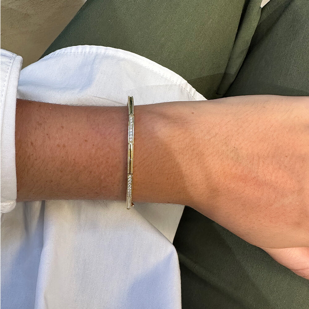 Close-up of a wrist wearing a gold and diamond bracelet designed by Penny Preville