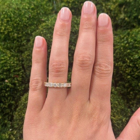woman wearing an 18K gold diamond ring with a green moss background