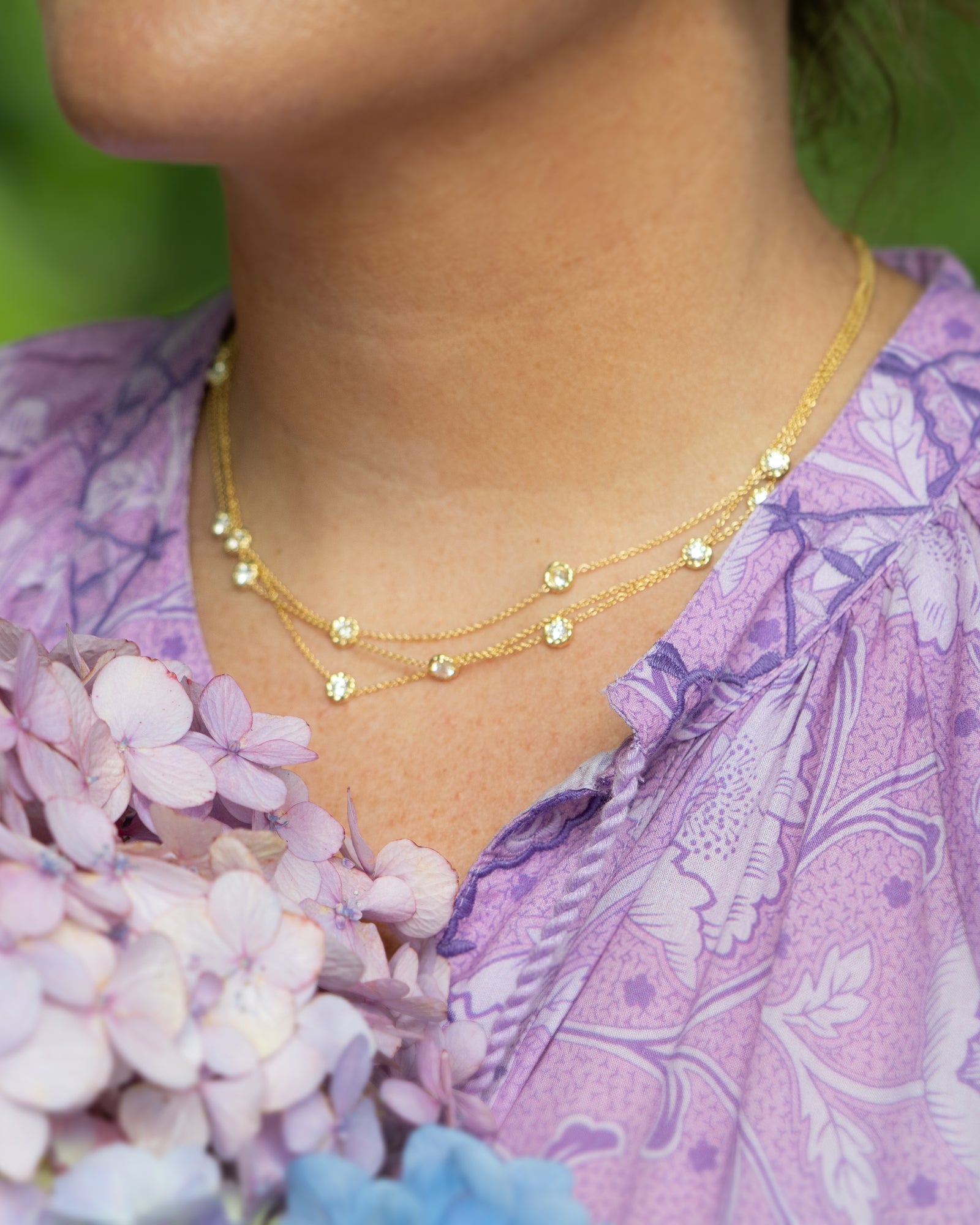 Gold station necklace worn with a lavender floral top