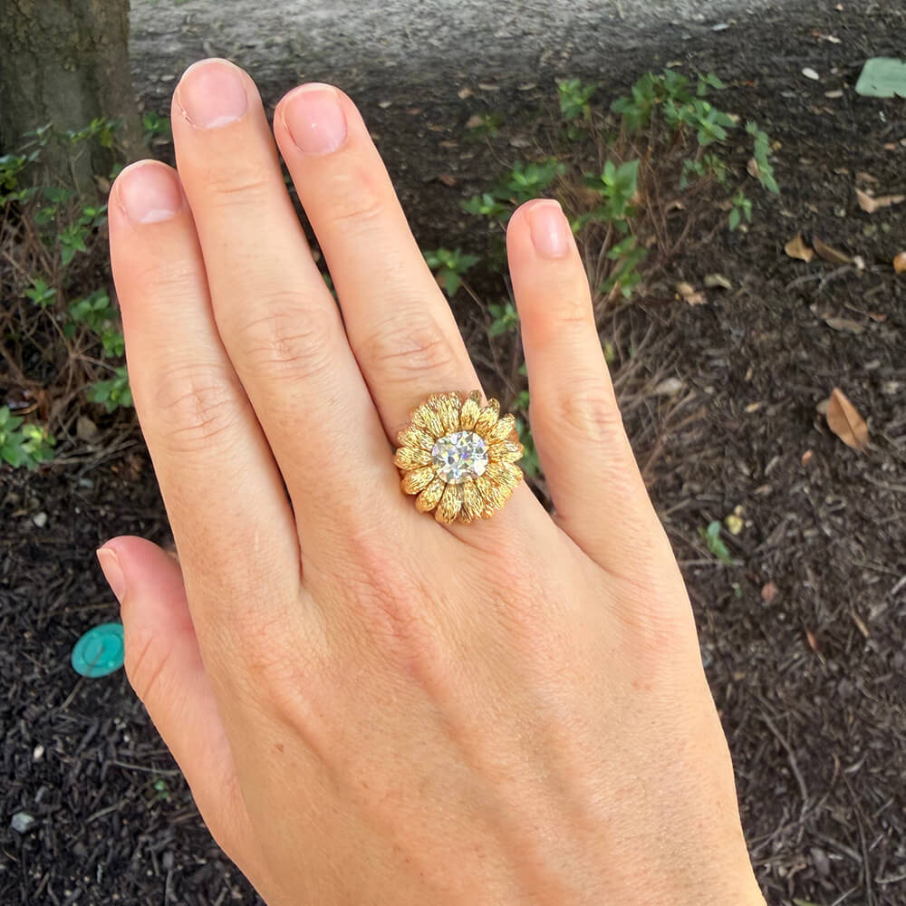 An estate 18K yellow gold flower-shaped ring with a clear center cushion cut diamond, 