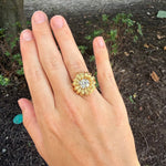 An estate 18K yellow gold flower-shaped ring with a clear center cushion cut diamond, 