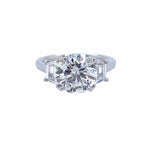 A custom-designed platinum round diamond ring with a trapezoid side stone, displayed against a white background.
