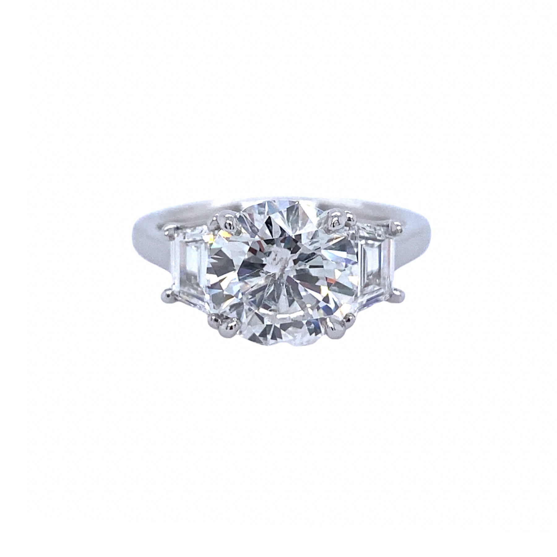 A custom-designed platinum round diamond ring with a trapezoid side stone, displayed against a white background.