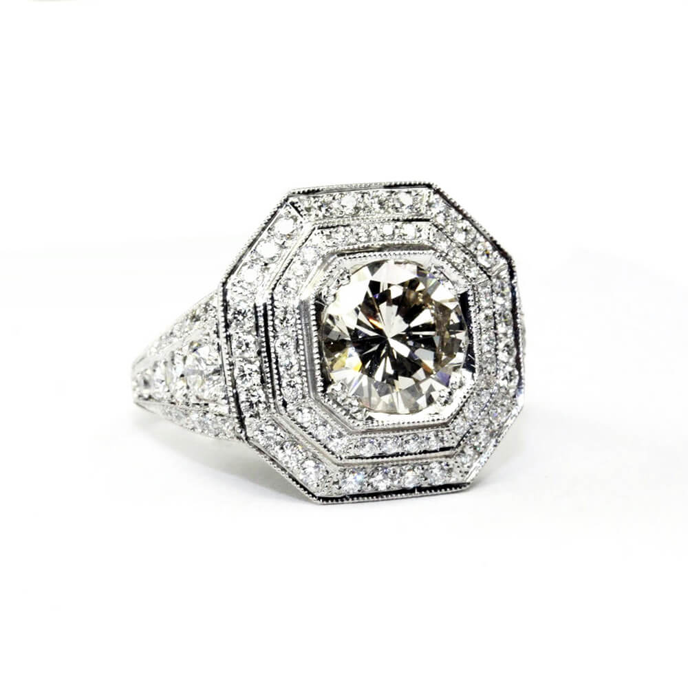 Diamond ring with a large central round diamond and smaller diamonds in an octagonal halo on a white background
