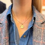 Woman wearing a gold necklace with a circular pendant.