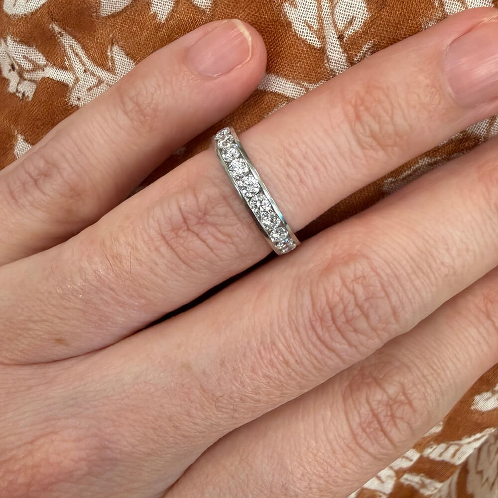 woman wearing a platinum diamond eternity band ring on a patterned fabric background