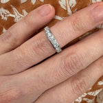 woman wearing a platinum diamond eternity band ring on a patterned fabric background