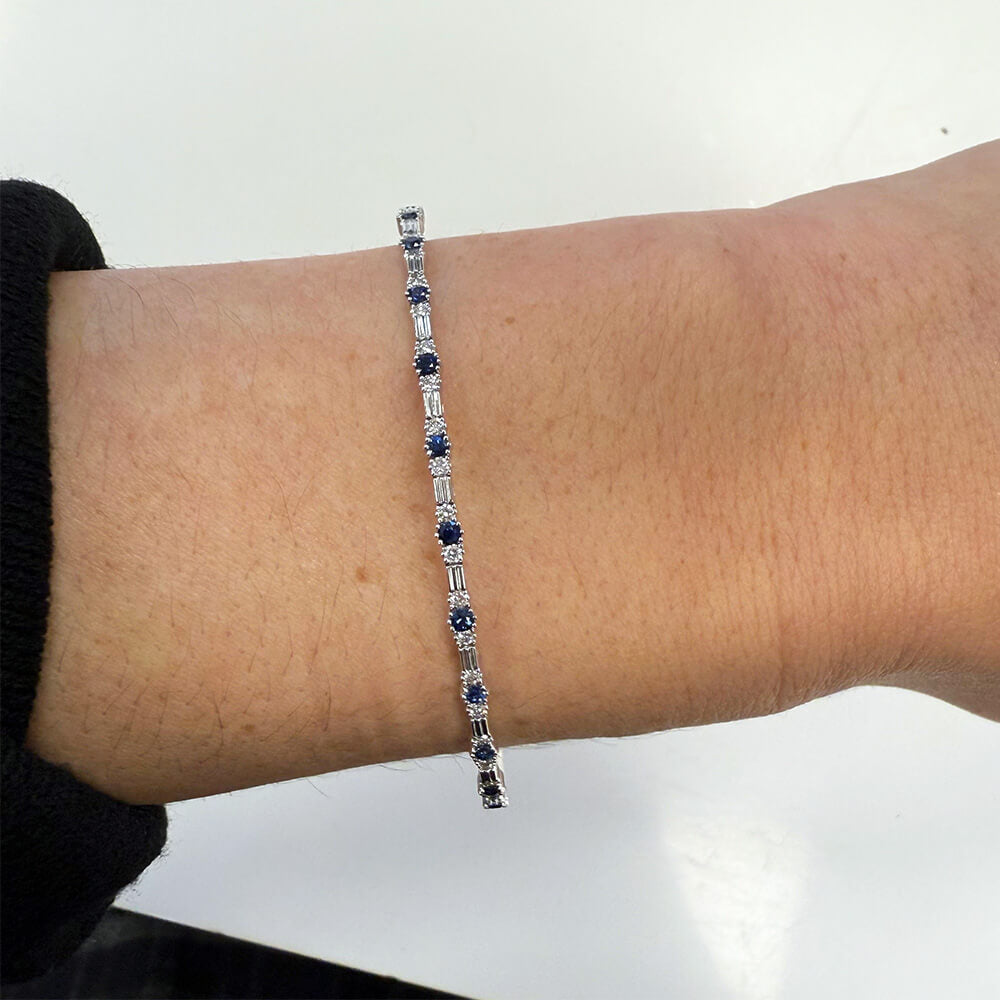 14K white gold bracelet with blue sapphires and diamonds on a wrist against a white background