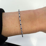 14K white gold bracelet with blue sapphires and diamonds on a wrist against a white background