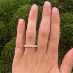 woman wearing an 18K gold diamond ring with a green blurred background
