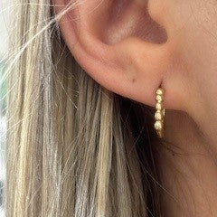 Close-up of an ear wearing a 14K gold hoop earring 