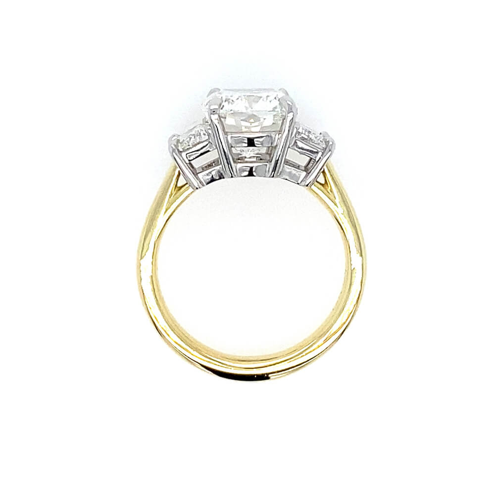 An 18K yellow gold and platinum ring featuring a rectangular clear diamond in a four-prong setting with smaller accent stones on either side, shown against a plain white background.