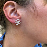 Close-up of an ear wearing white gold diamond clover earrings