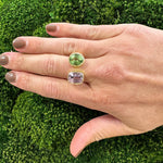 woman wearing a ring with kunzite and tourmaline gemstones on a green moss background