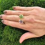 woman wearing a ring with kunzite and tourmaline gemstones on a green moss background
