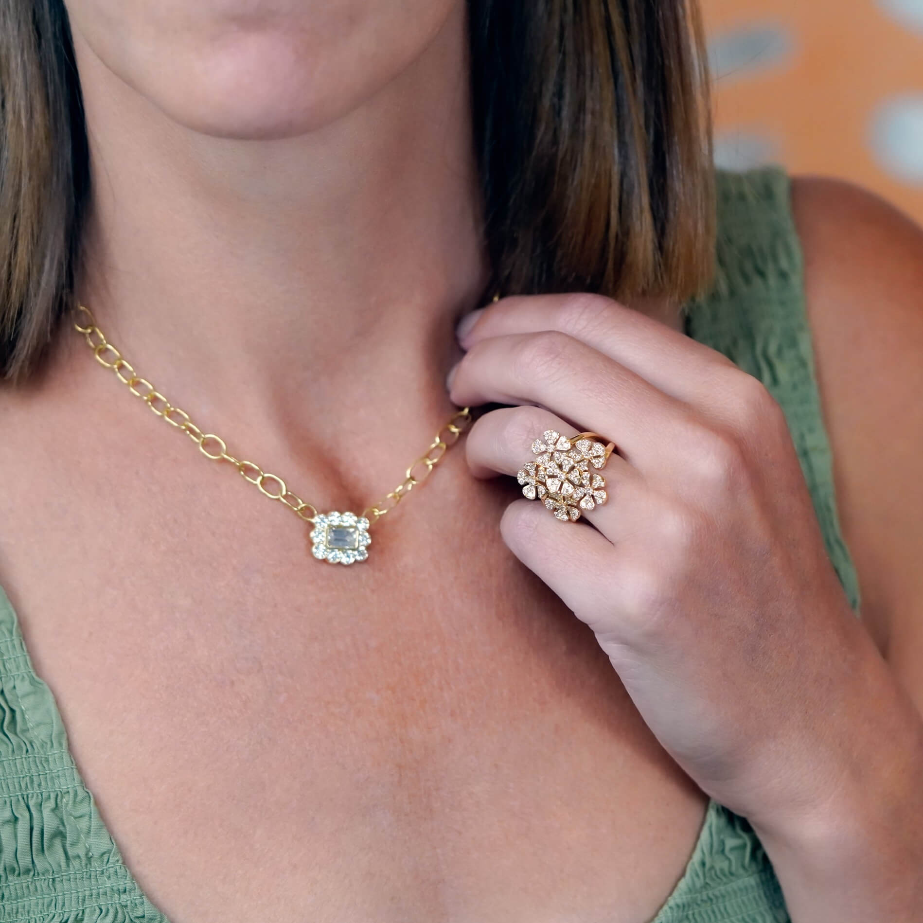 Woman wearing a gold necklace and ring with a green top.