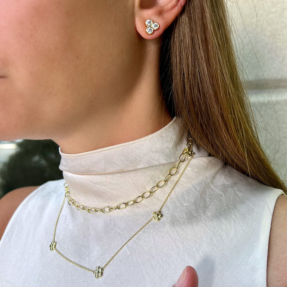 Close-up of a woman wearing 18K gold chain necklaces and earrings designed by Laura Pearce