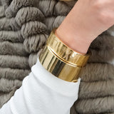 Woman wearing two polished flat gold bangles