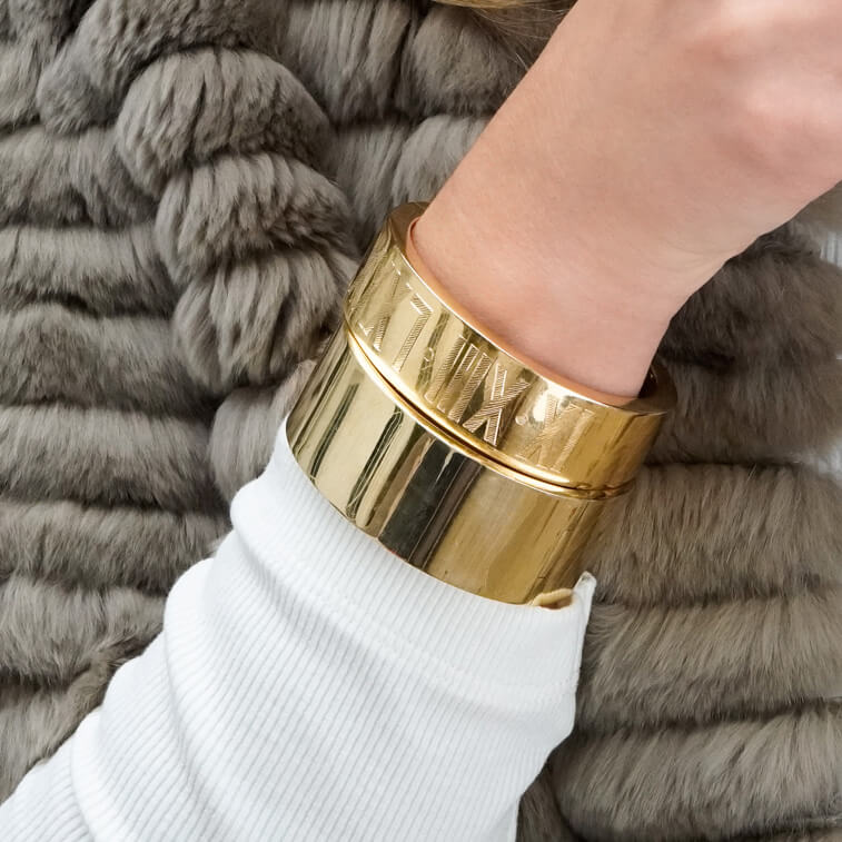 Woman wearing two polished flat gold bangles
