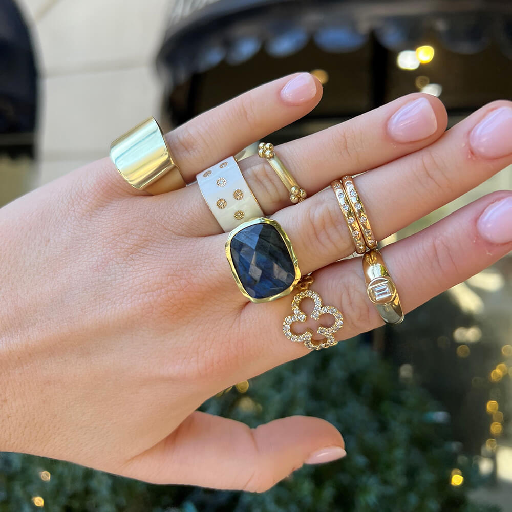 Hand wearing multiple rings with a blurred outdoor background