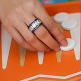 Hand with multiple platinum diamond and sapphire rings on a game board 