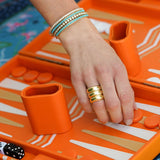 Hand with three 14K gold Dome Band Rings on an orange game board