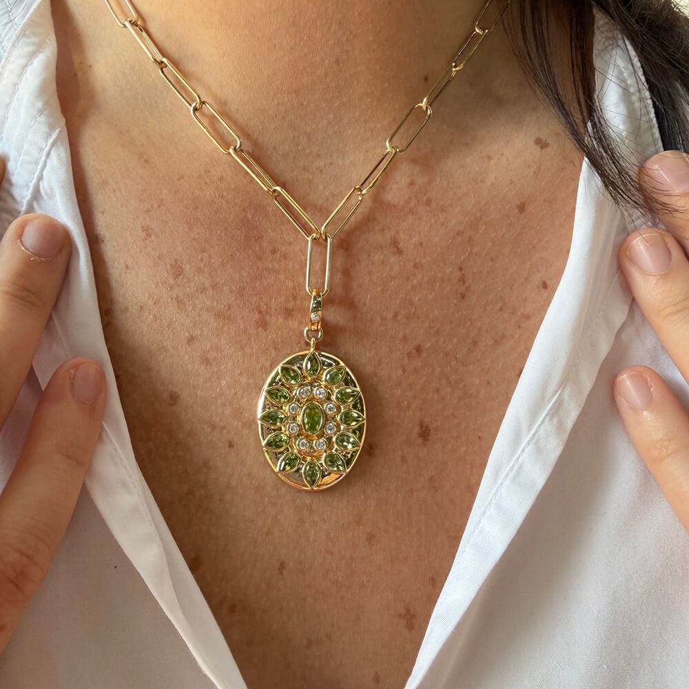 A close-up of a 14K gold chain necklace with a 14K yellow gold peridot and diamond oval pendant