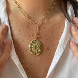 A close-up of a 14K gold chain necklace with a 14K yellow gold peridot and diamond oval pendant