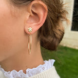 woman wearing 18K gold hoop earrings with single diamond in center of flower design on stud