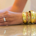Woman wearing several 18K yellow gold bracelets designed by Laura Pearce