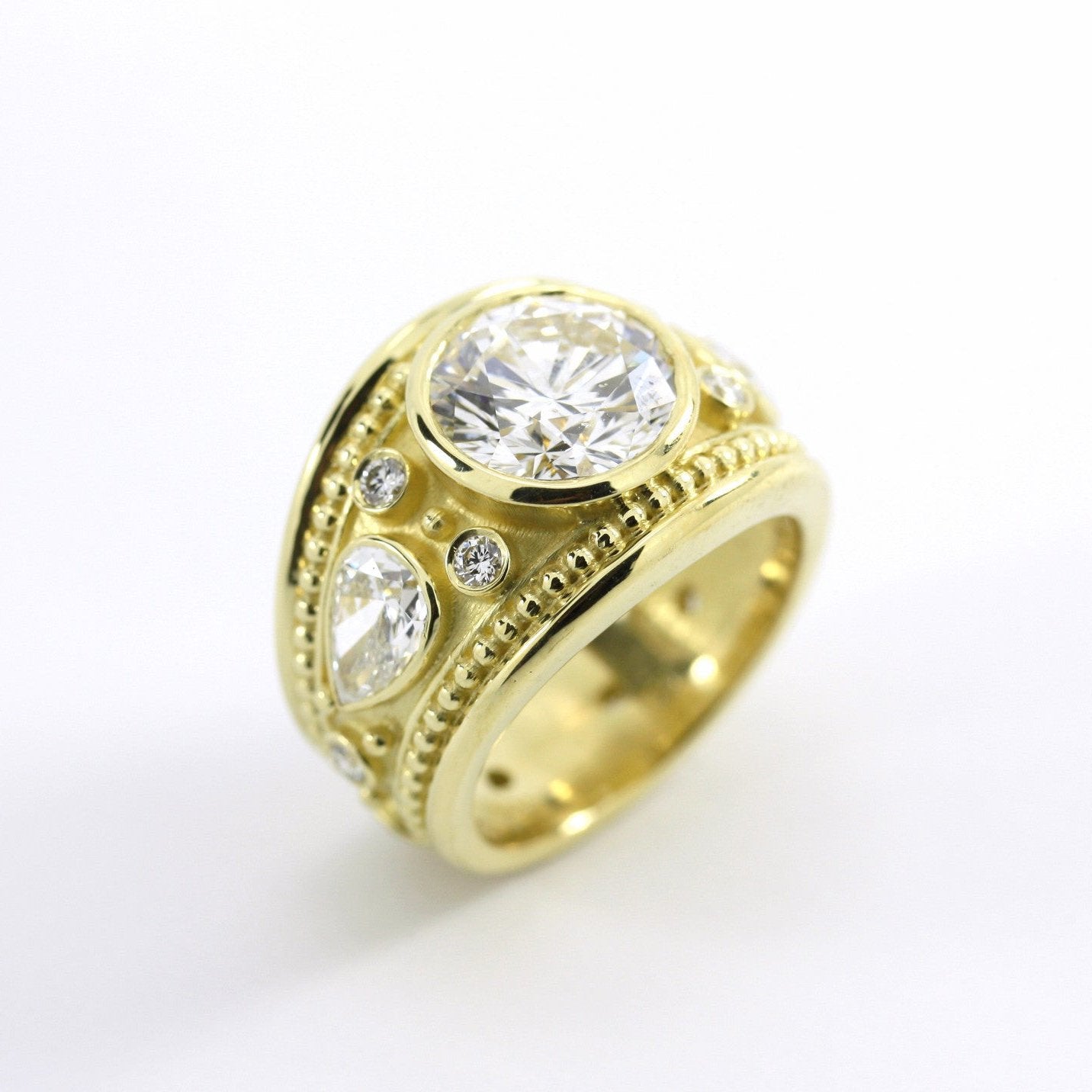 An 18kt yellow gold band ring with a central diamond and two teardrop diamonds set in the band.