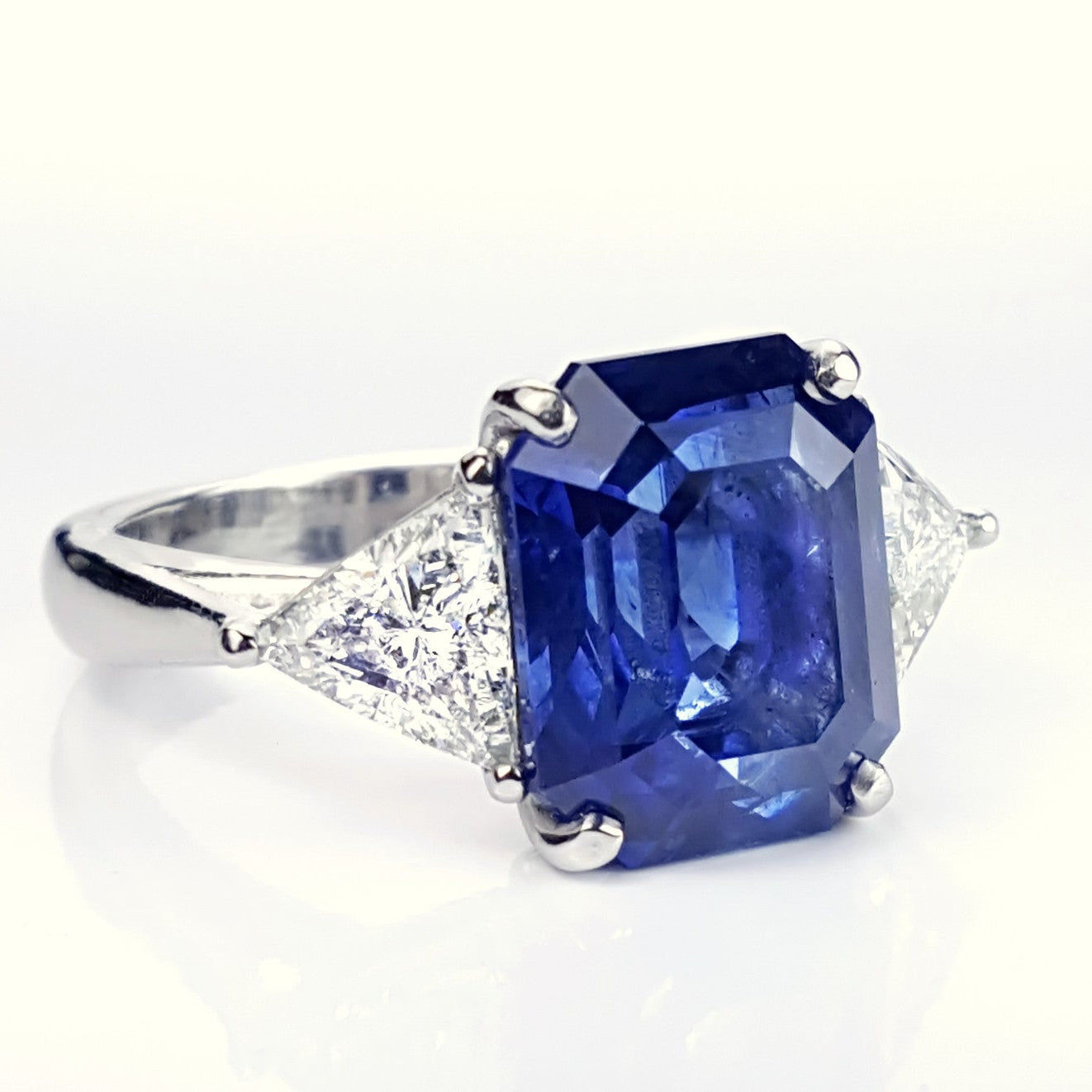custom designed platinum ring with large emerald cut sapphire flanked by triangular diamonds