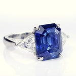 custom designed platinum ring with large emerald cut sapphire flanked by triangular diamonds