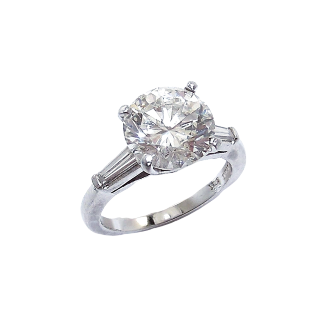 A platinum round brilliant cut diamond with tapered baguettes on the side
