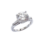 A platinum round brilliant cut diamond with tapered baguettes on the side