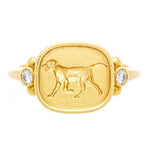 An 18k yellow gold ring featuring an engraved dog design on the top with two small diamonds on the sides.