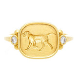 An 18k yellow gold ring featuring an engraved dog design on the top with two small diamonds on the sides.