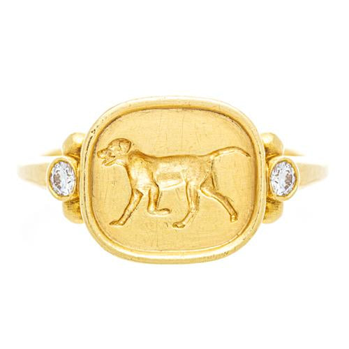 An 18k yellow gold ring featuring an engraved dog design on the top with two small diamonds on the sides.