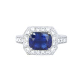 A platinum ring featuring a large blue sapphire center stone, flanked by smaller diamonds