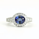 A custom oval sapphire and diamond ring with a platinum band, featuring a large blue sapphire in an oval setting, flanked by smaller round-cut diamonds.
