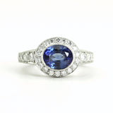 A custom oval sapphire and diamond ring with a platinum band, featuring a large blue sapphire in an oval setting, flanked by smaller round-cut diamonds.