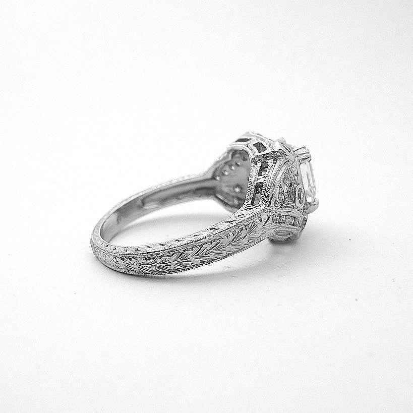 A platinum Asscher cut diamond ring with a halo effect, featuring smaller diamonds set around the main stone.