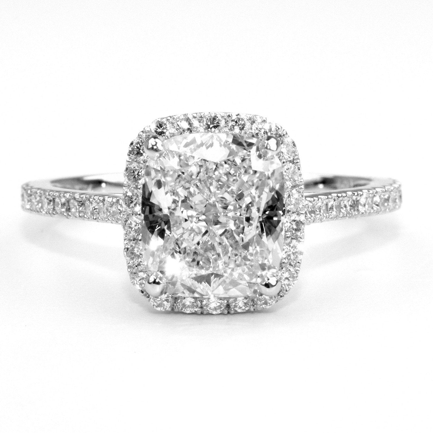 A platinum ring with a cushion cut diamond center stone, surrounded by smaller diamonds 