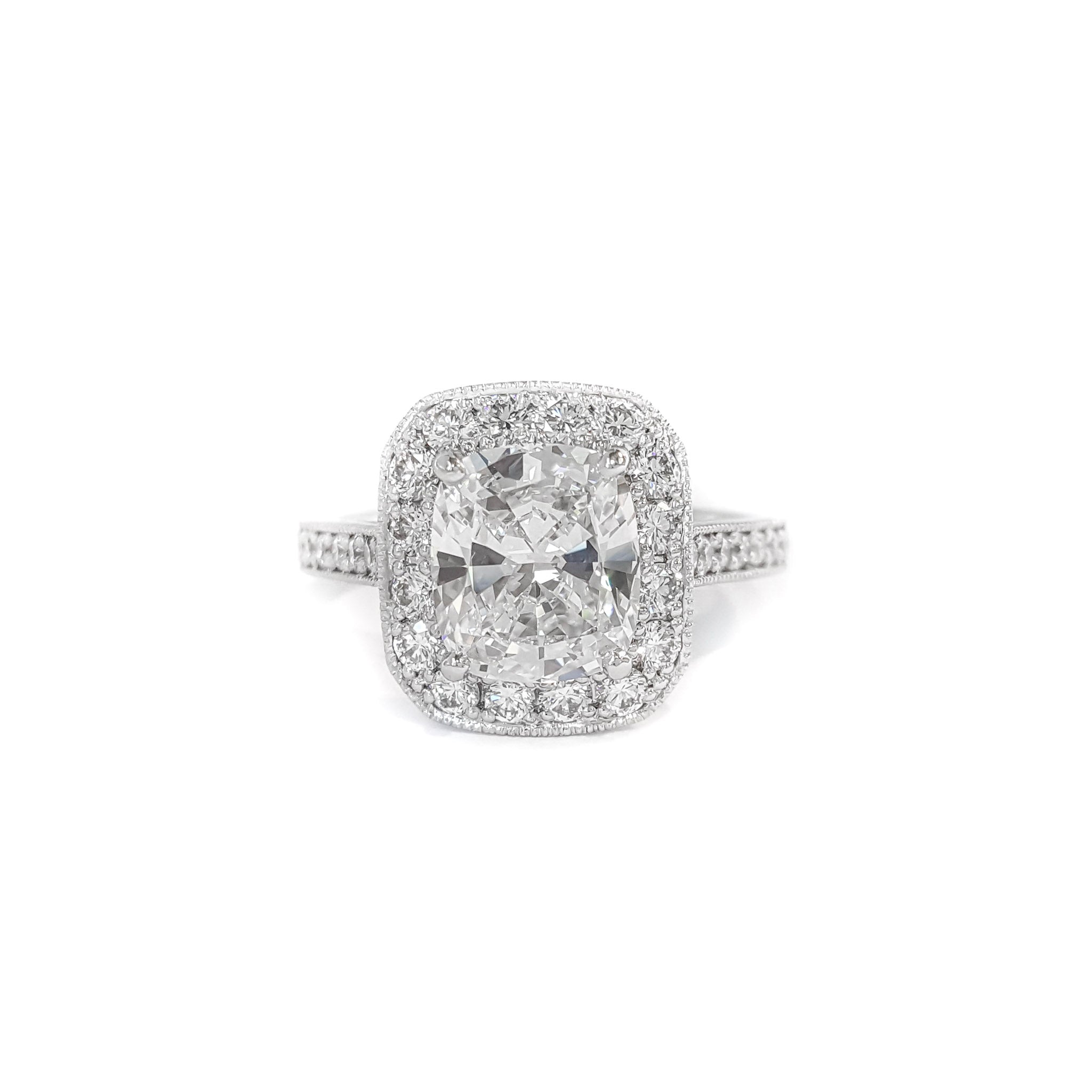 A platinum cushion cut diamond ring with a bead set diamond halo.